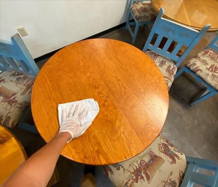 man wiping down wooden table