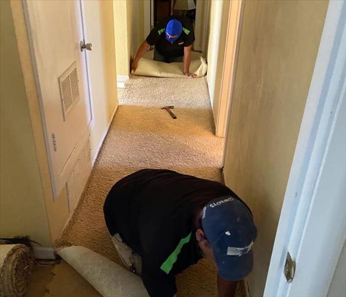 two men ripping up carpet in hallway