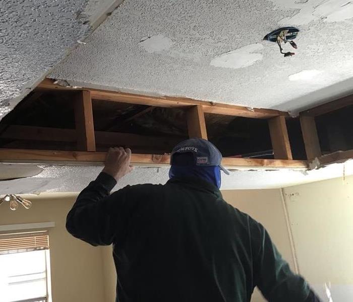 male SERVPRO employee removing part of ceiling 