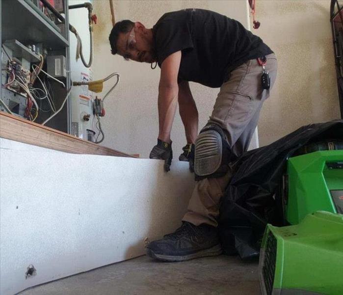 Male SERVPRO employee removing drywall